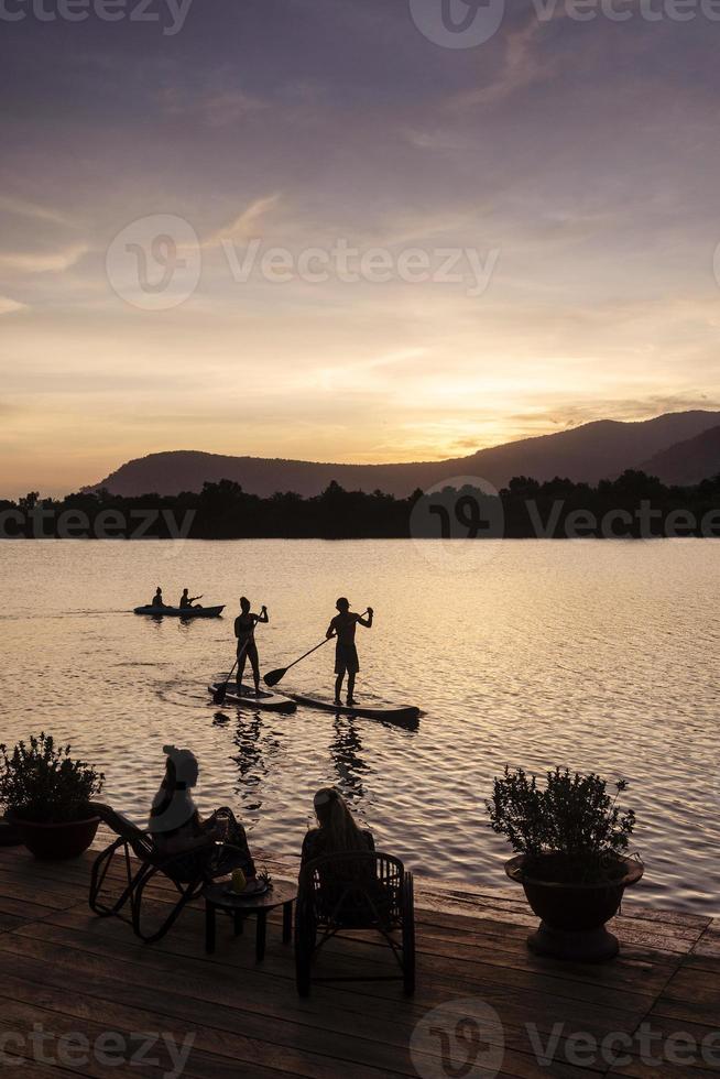 Kampot river view in Cambodia with SUP stand up paddle boarding tourists at sunset photo