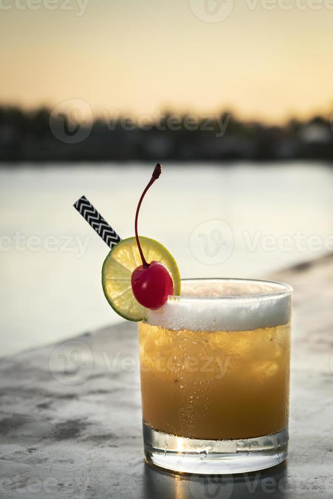 Peach screwdriver mixed vodka cocktail drink outdoors at sunset bar photo