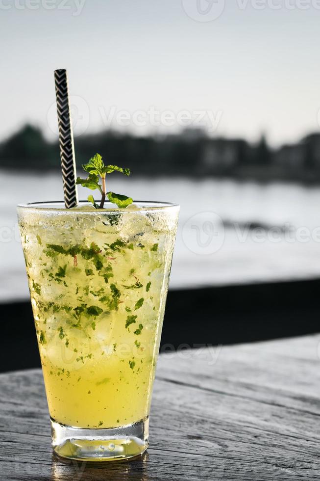 Orange mojito summer cocktail drink on outdoor riverside bar table photo