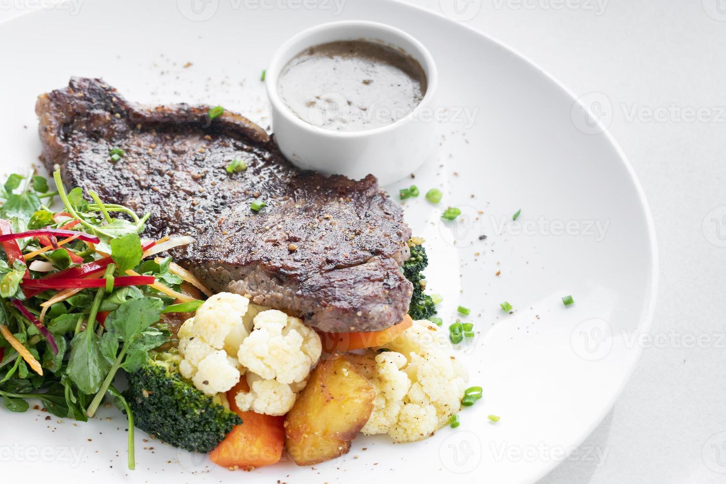 Premium beef steak with steamed vegetables and mushroom sauce gourmet meal on white plate photo