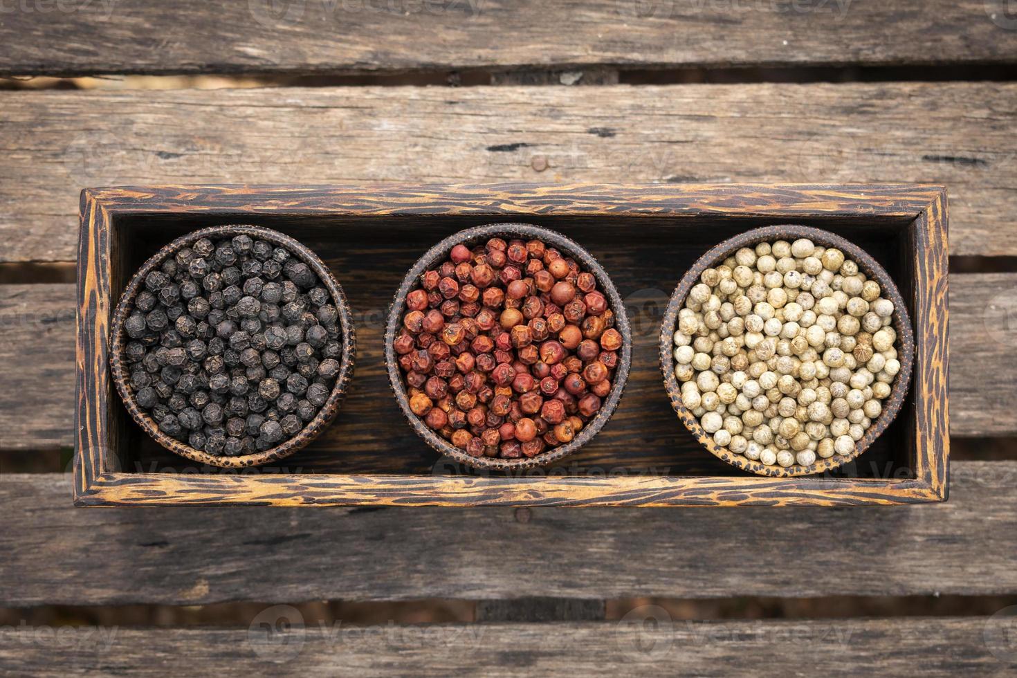 Organic Kampot white red and black peppercorns in natural rustic style wood display in Cambodia photo