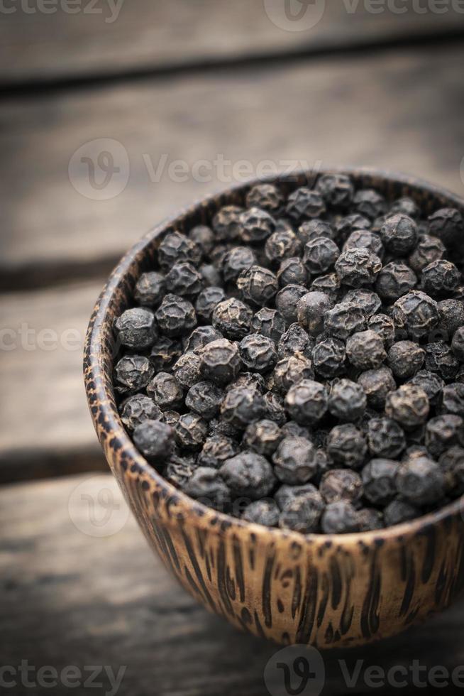 Organic Kampot dried black pepper corns in traditional wood bowl in Cambodia photo