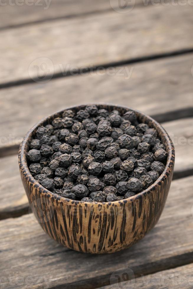 Organic Kampot dried black pepper corns in traditional wood bowl in Cambodia photo