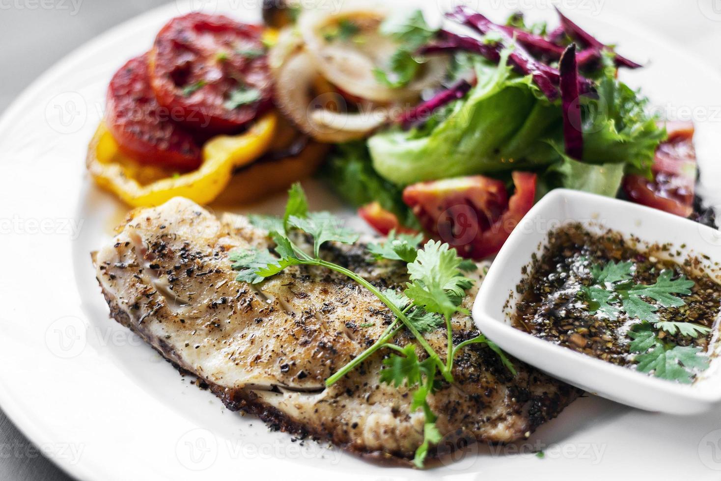 Tilapia fish fillet with mixed salad grilled vegetables and herb Vinaigrette sauce photo