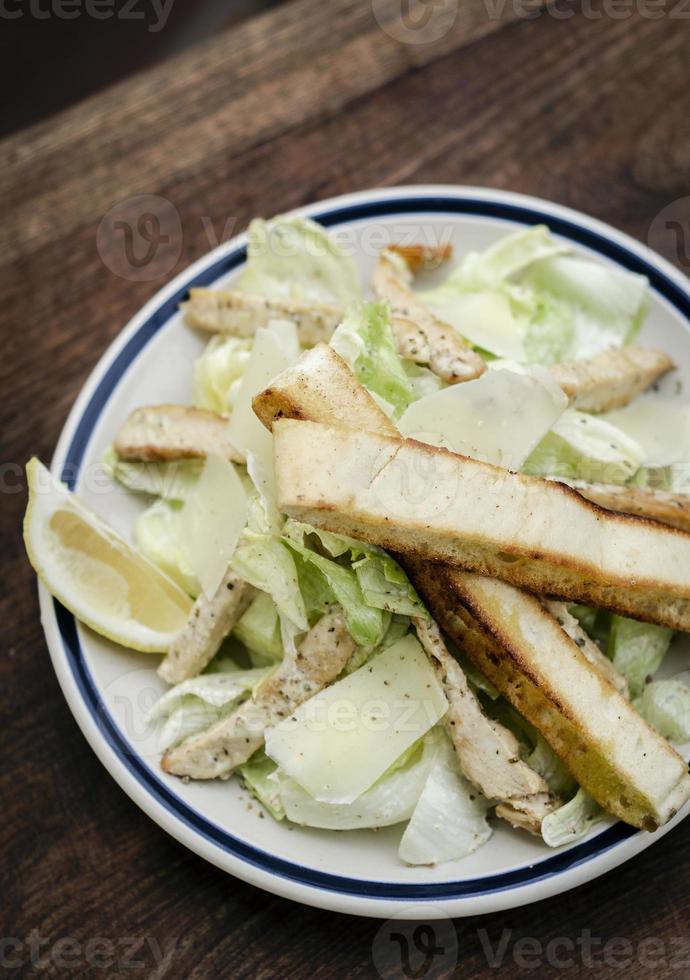 Ensalada César de pollo orgánico saludable simple sobre mesa de madera foto