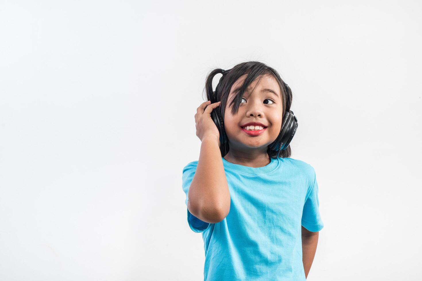 Little girl listening to music on wireless headphones. photo