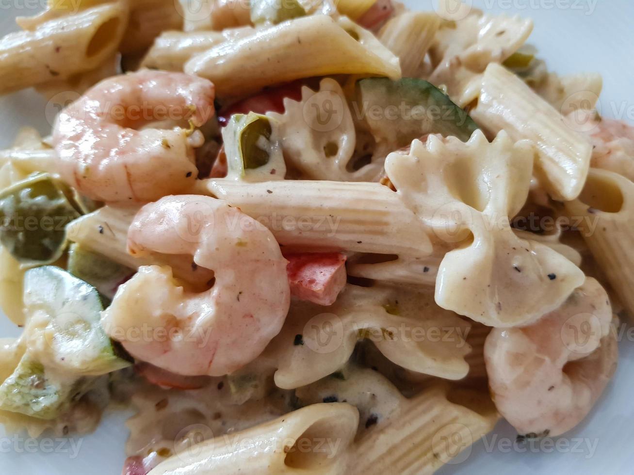 Sartén de fideos de colores con verduras y gambas tigre blancas foto