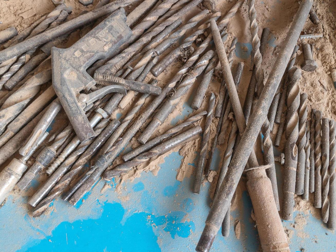 Old wood drill bits and steel tools on a table with dust and chips photo