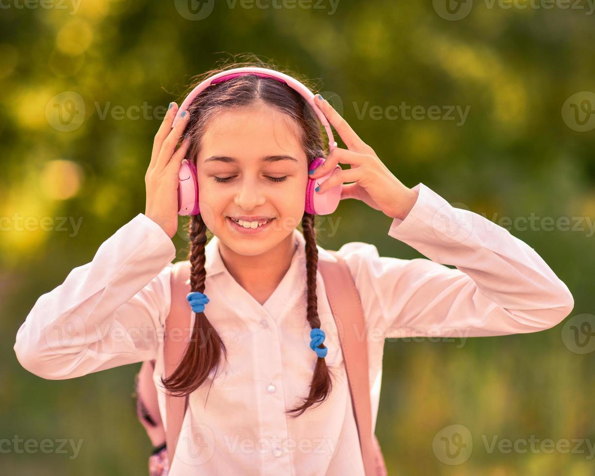 Adolescente escuchando música al aire libre con auriculares inalámbricos foto
