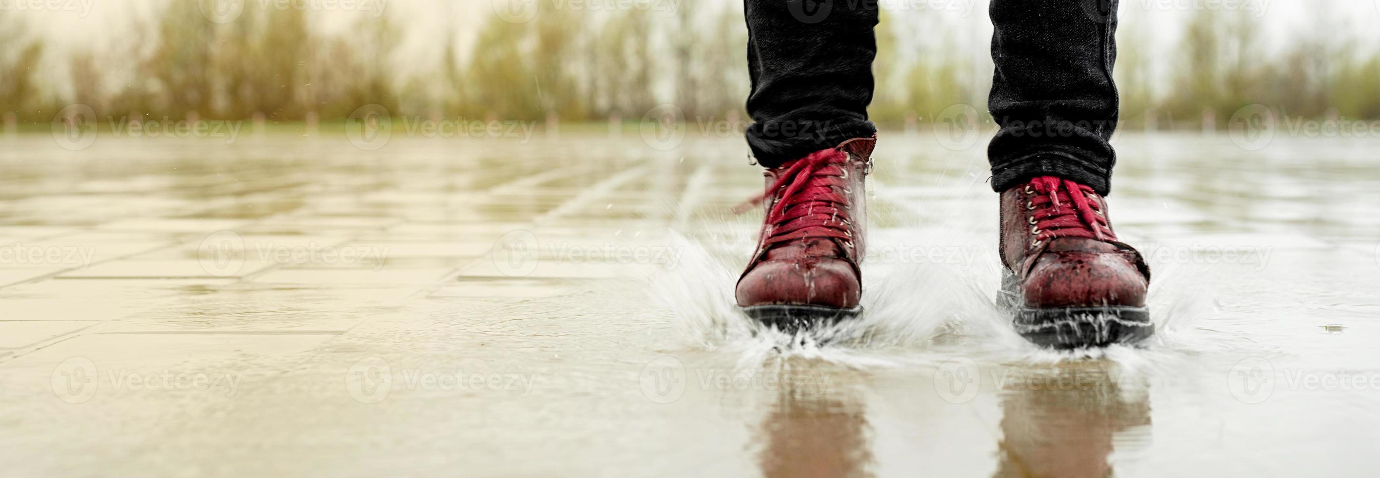 Woman playing in the rain, jumping in puddles with splashes photo