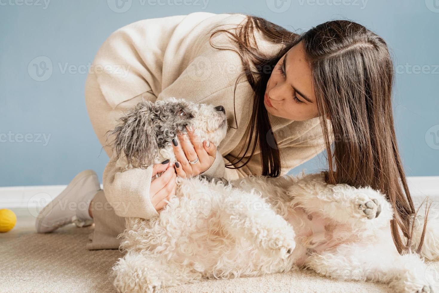 Bella mujer con perro juguetón abrazando en casa foto