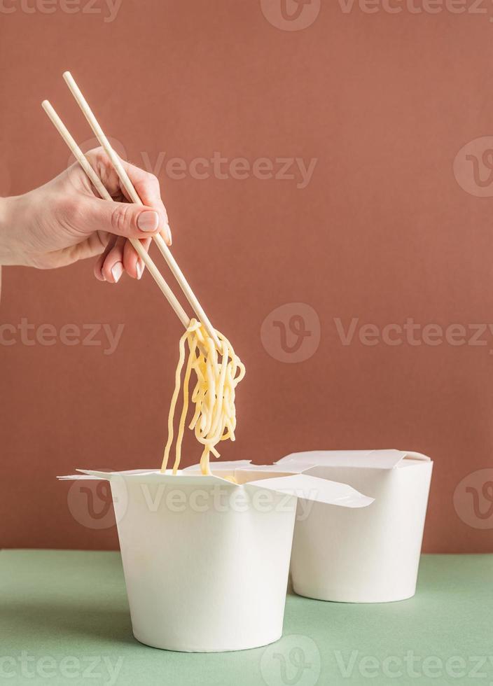 Woman hand holding noodles with chopsticks photo