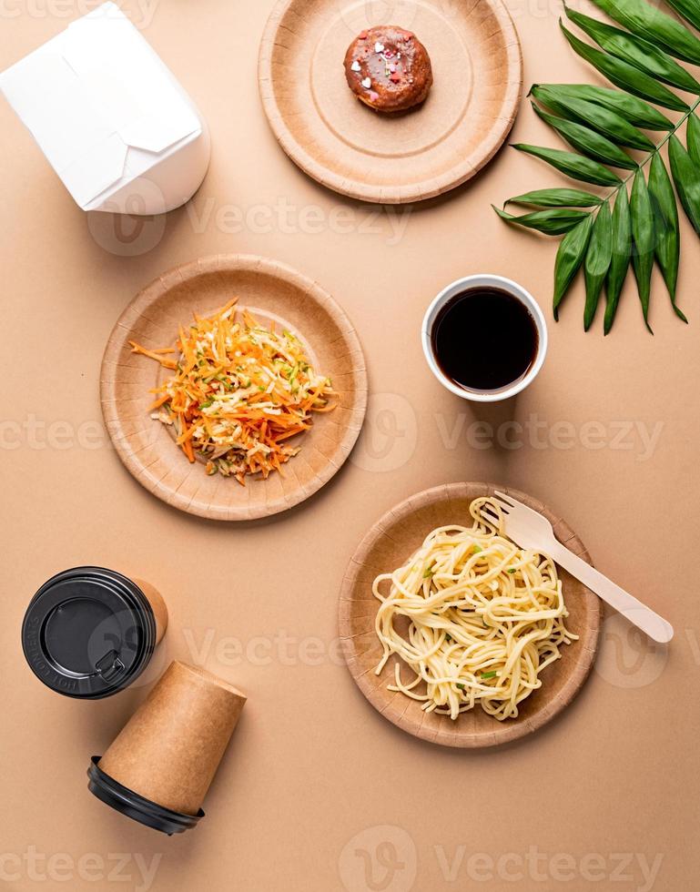 Eco friendly disposable tableware full of food on brown background photo