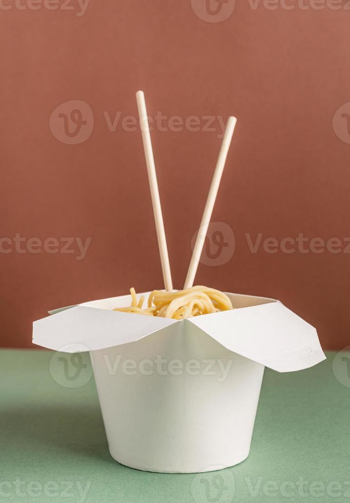 Caja de papel wok abierta con fideos y palillos para un diseño simulado foto