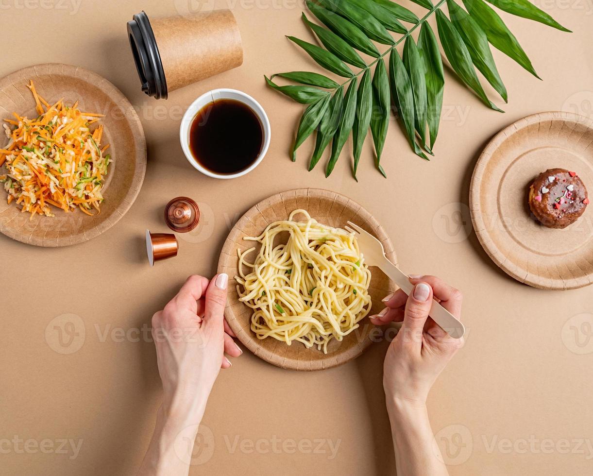 Vajilla desechable ecológica llena de comida sobre fondo marrón foto