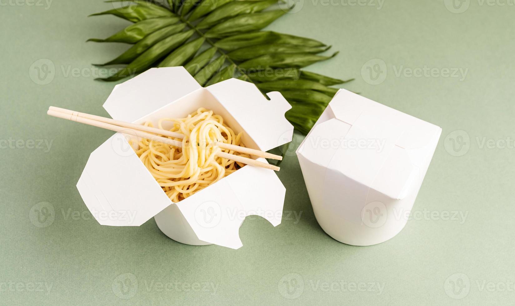 Opened WOK paper box with noodles and chopsticks photo
