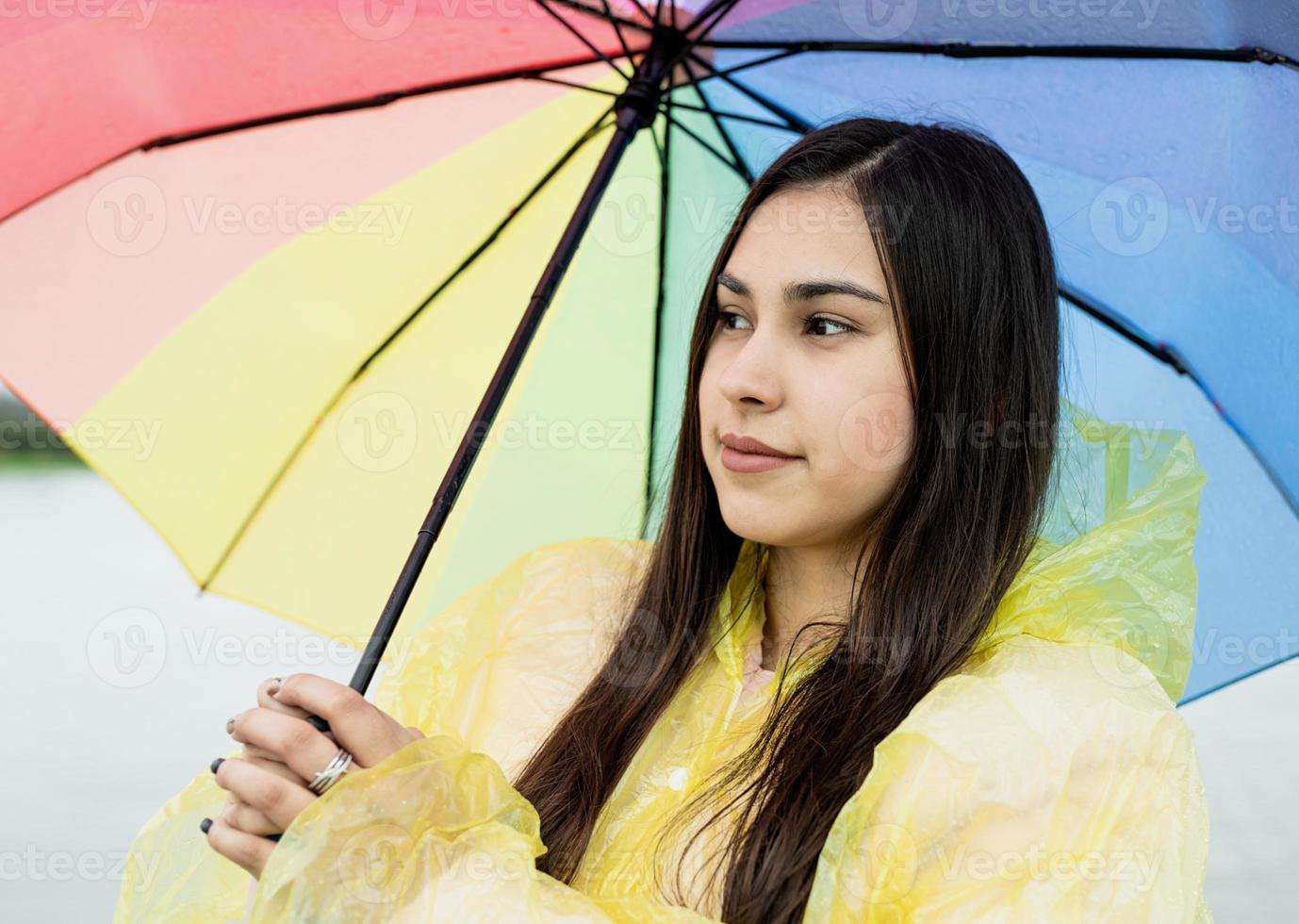 Beautiful brunette woman holding colorful umbrella out in the rain photo