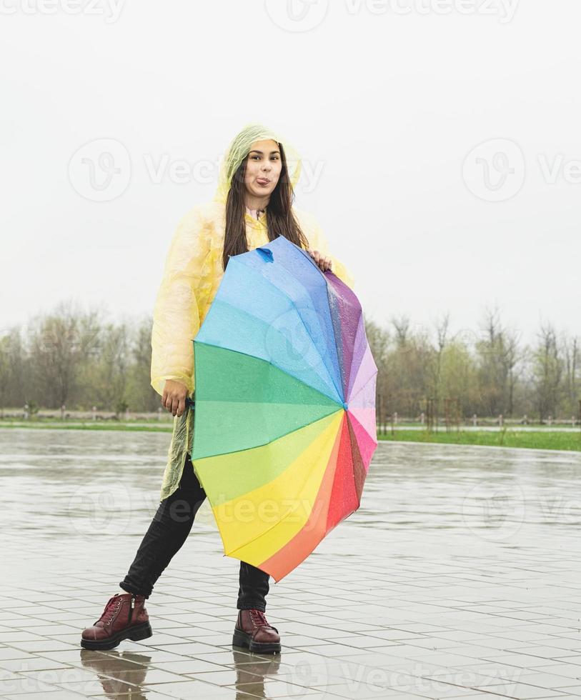 Beautiful brunette woman holding colorful umbrella out in the rain photo