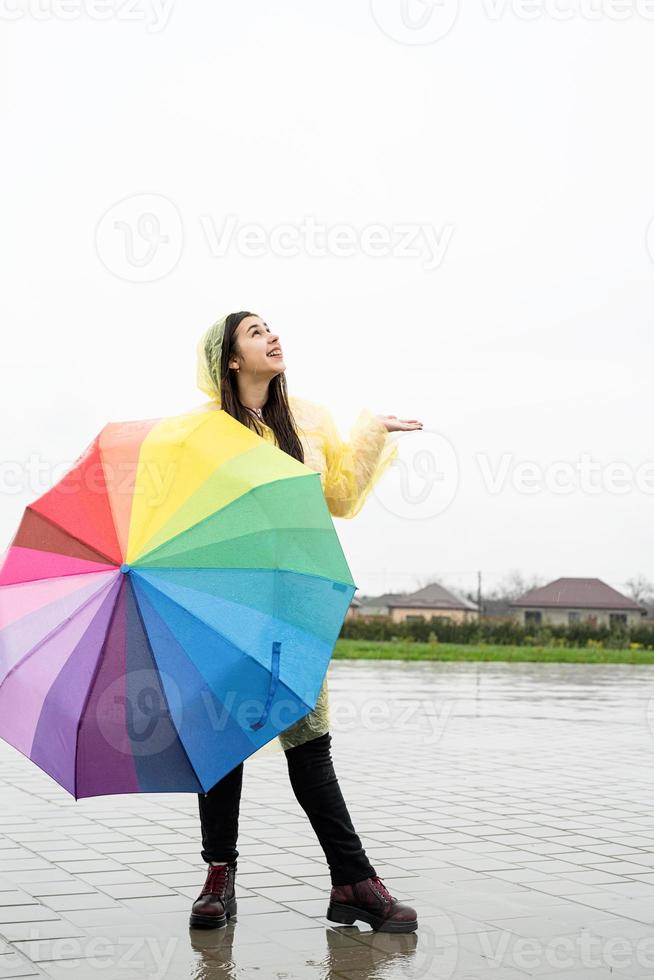 Beautiful brunette woman holding colorful umbrella out in the rain photo