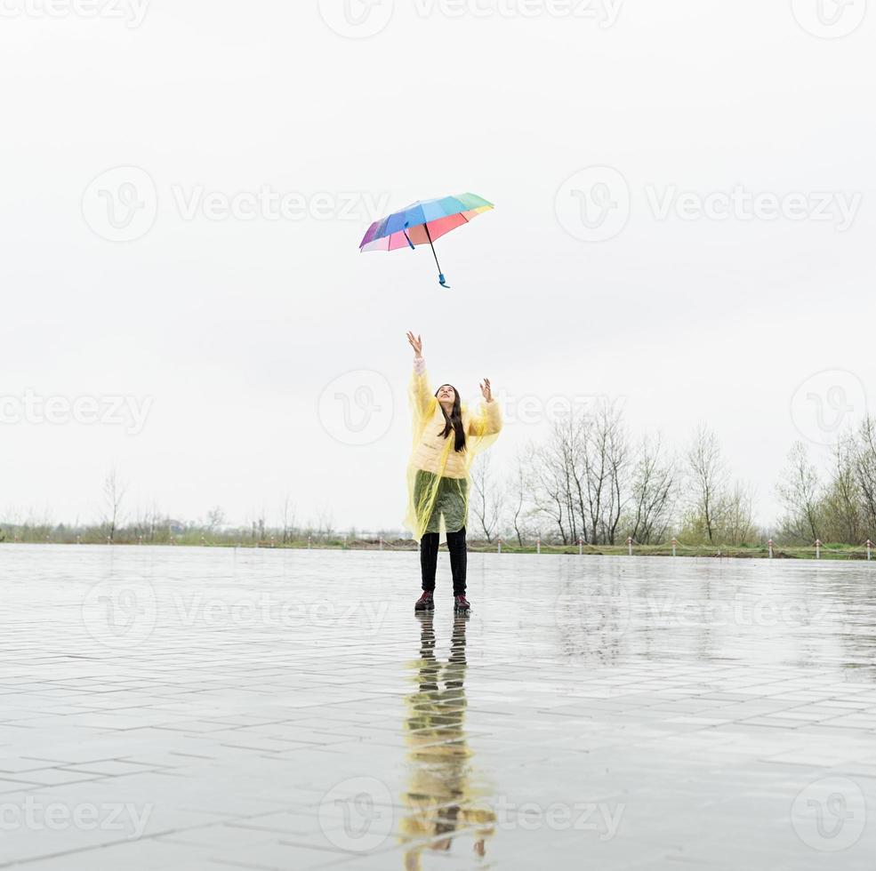 Hermosa mujer morena sosteniendo coloridos paraguas bajo la lluvia foto