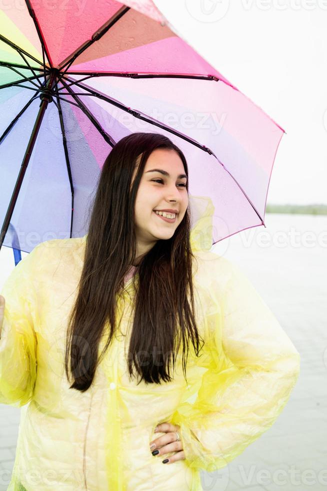 Beautiful brunette woman holding colorful umbrella out in the rain photo