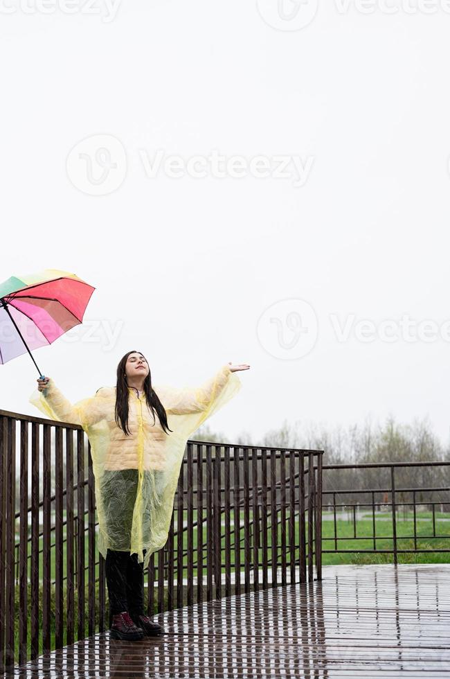 Beautiful brunette woman holding colorful umbrella out in the rain photo