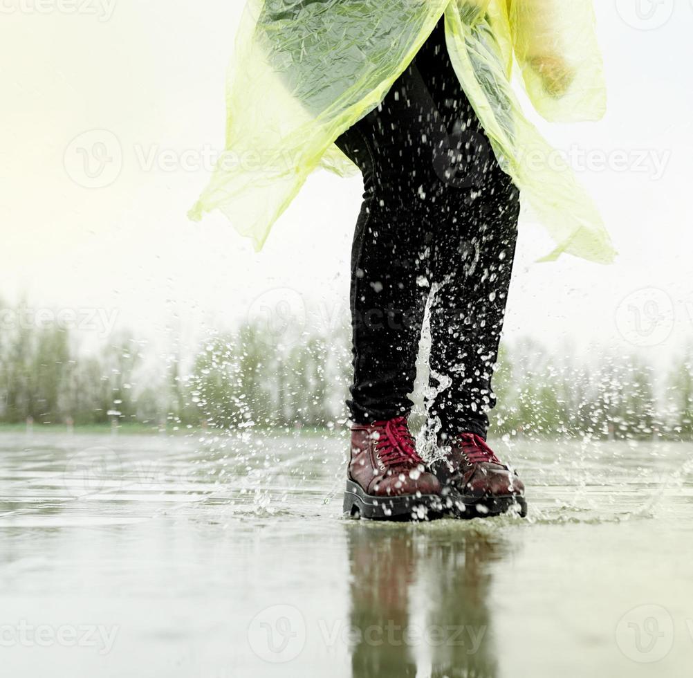 Woman playing in the rain, jumping in puddles with splashes photo