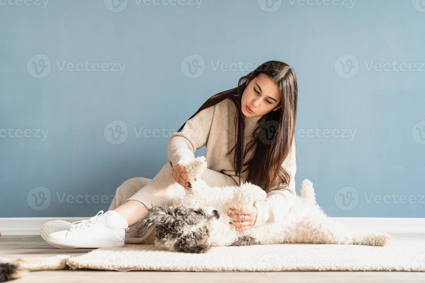 Bella mujer con perro juguetón abrazando en casa foto