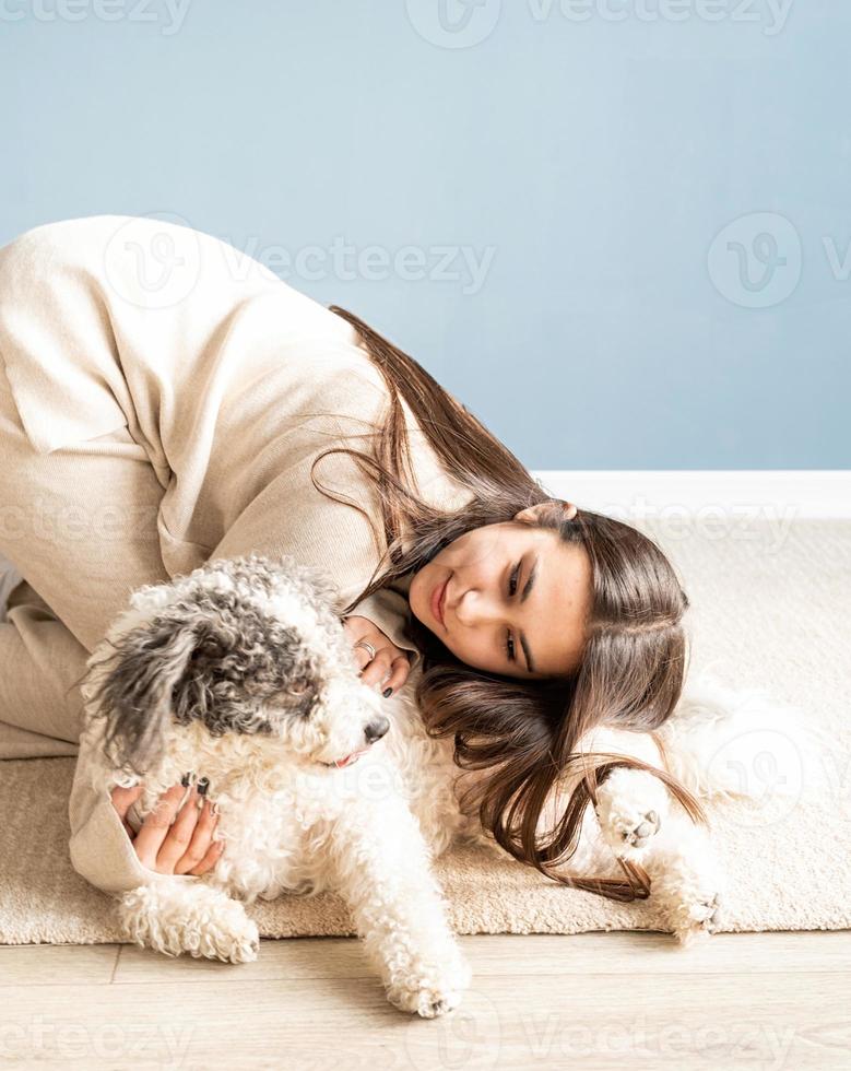 Bella mujer con perro juguetón abrazando en casa foto