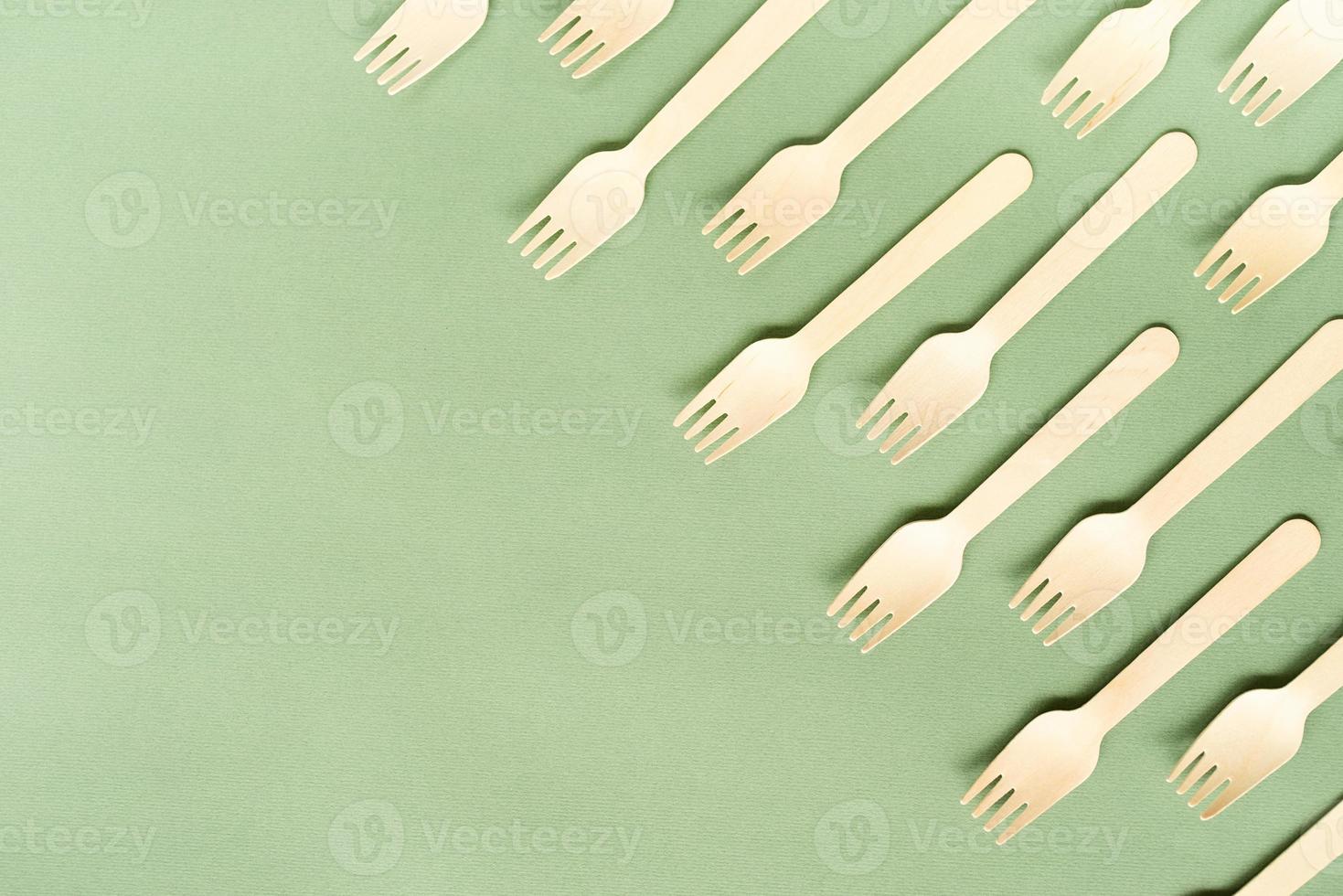 Disposable wooden forks top view on green background with copy space photo