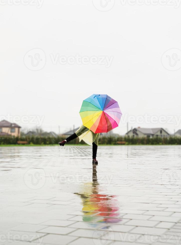 Mujer sosteniendo coloridos paraguas bailando bajo la lluvia foto