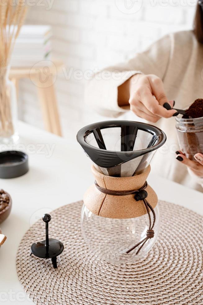 Woman brewing coffee in coffee pot photo
