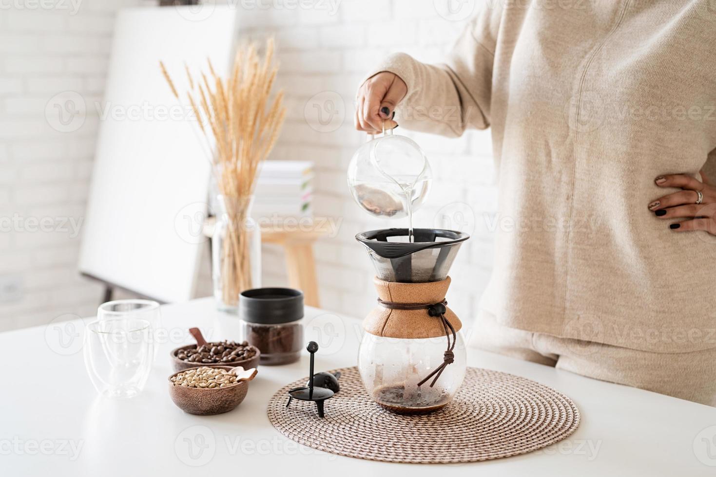 Woman brewing coffee in coffee pot, pouring hot water into the filter photo