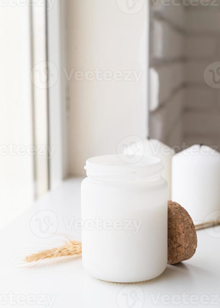White candle with wheat spikes on white background photo