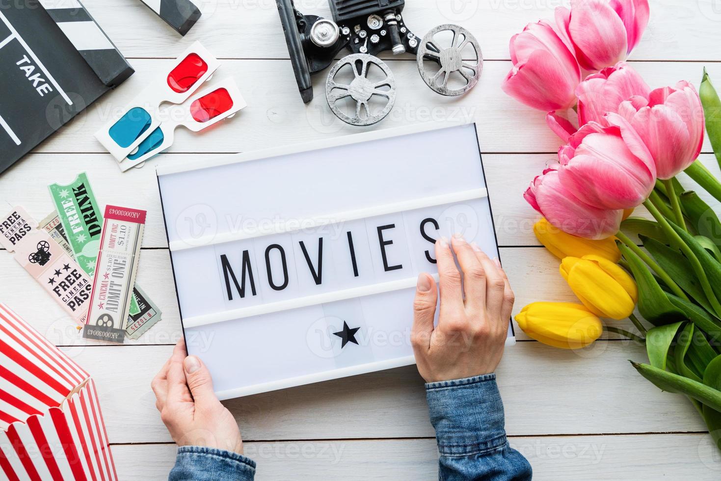 Woman's hands holding lightbox with word movies, clapper board photo