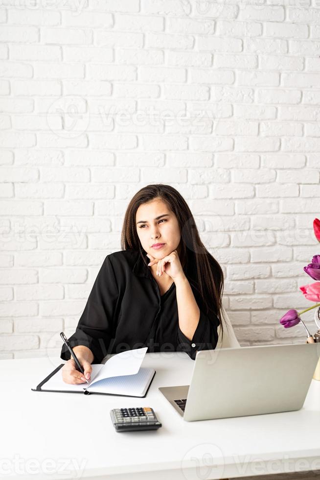 Woman florist writing in notebook, using laptop in the office photo