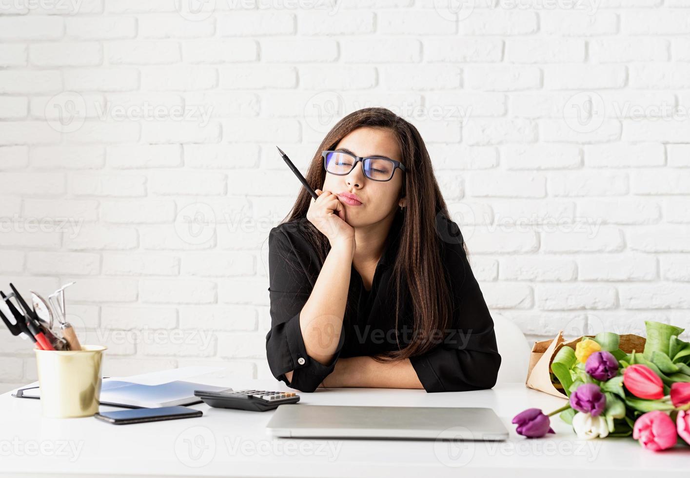 mujer que trabaja con flores en la oficina, pensando con los ojos cerrados foto