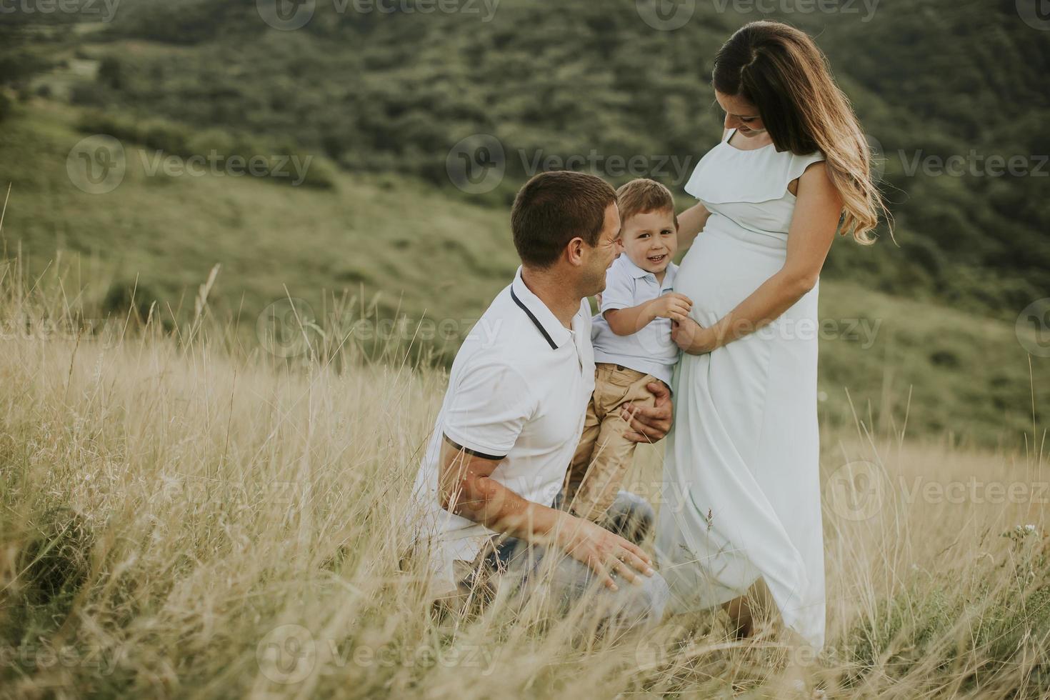 Familia joven con lindo niño divirtiéndose al aire libre en el campo foto