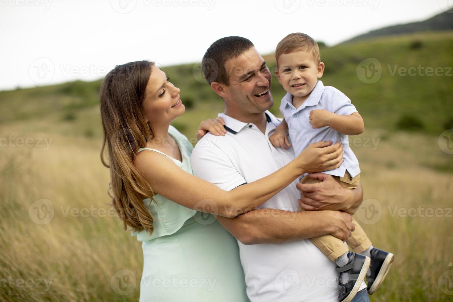 Familia joven con lindo niño divirtiéndose al aire libre en el campo foto