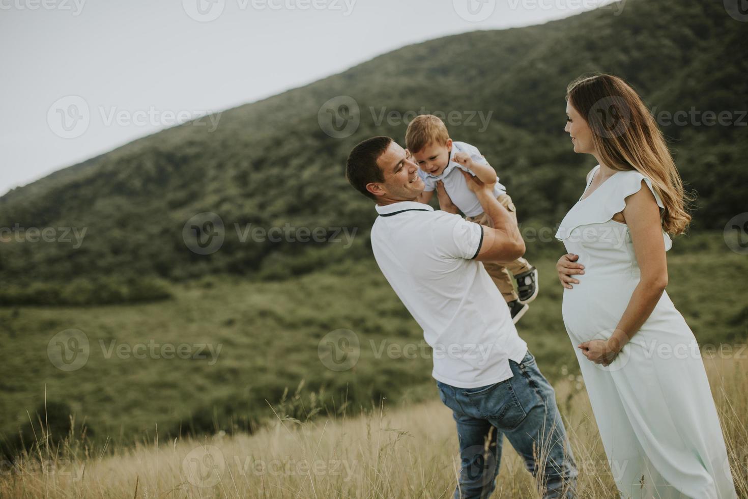 Familia joven con lindo niño divirtiéndose al aire libre en el campo foto