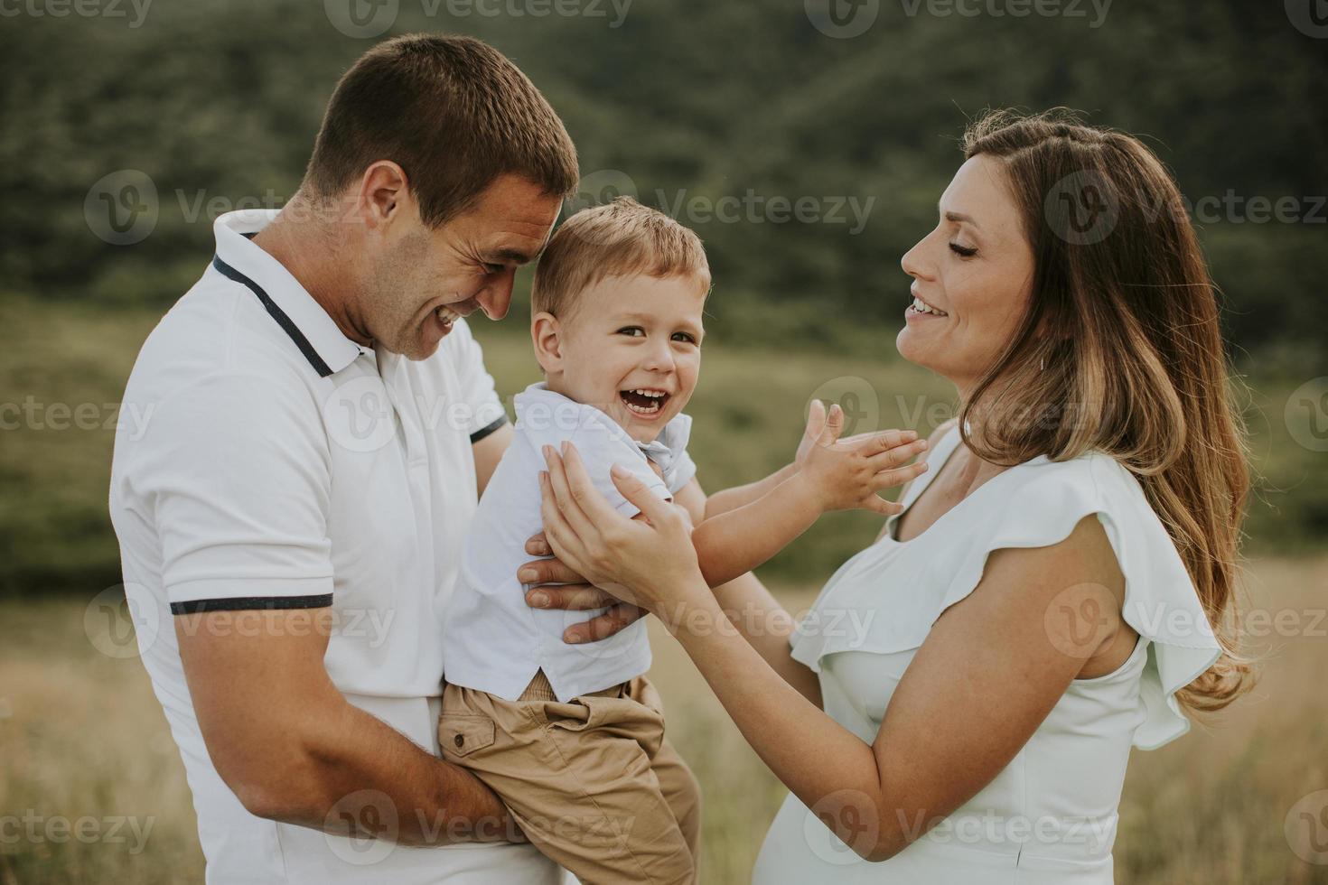 Familia joven con lindo niño divirtiéndose al aire libre en el campo foto