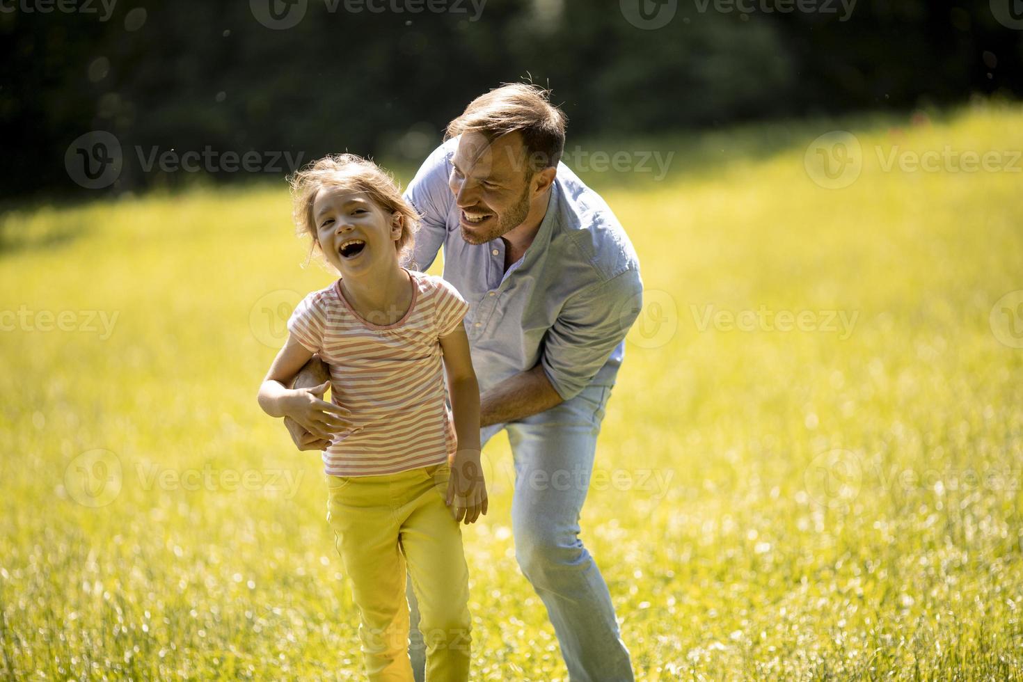 Padre con hija divirtiéndose en el césped del parque foto