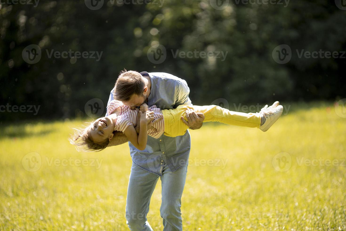 Padre con hija divirtiéndose en el césped del parque foto