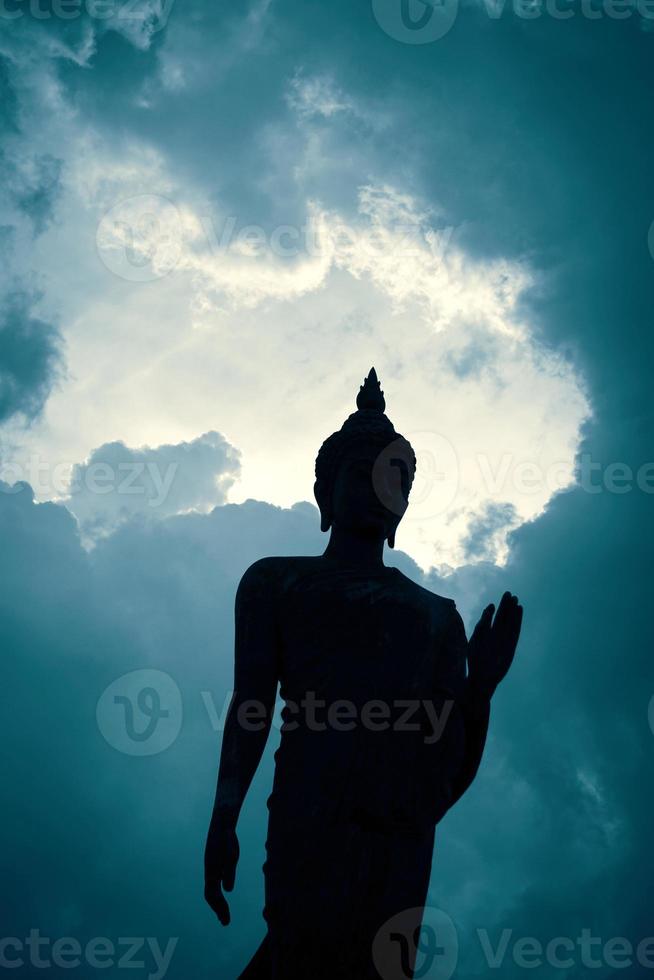 Silhouette of Buddha statue on blue sky background photo