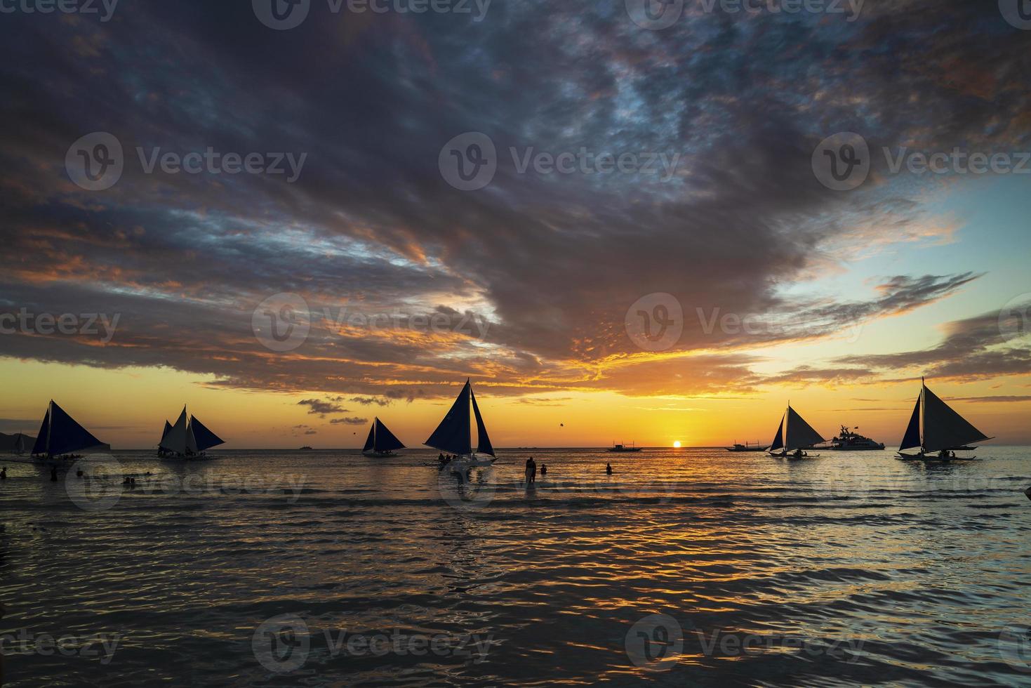 Hermoso atardecer tropical con veleros y turistas en la isla de Boracay, Filipinas foto