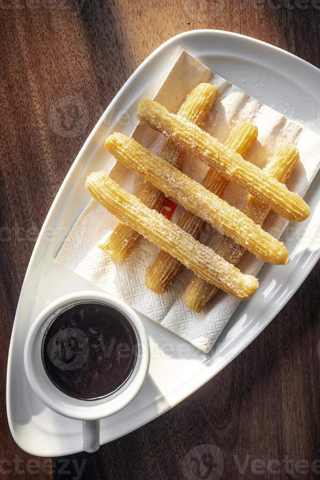 Churros con chocolate dulce tradicional español desayuno en mesa de madera foto