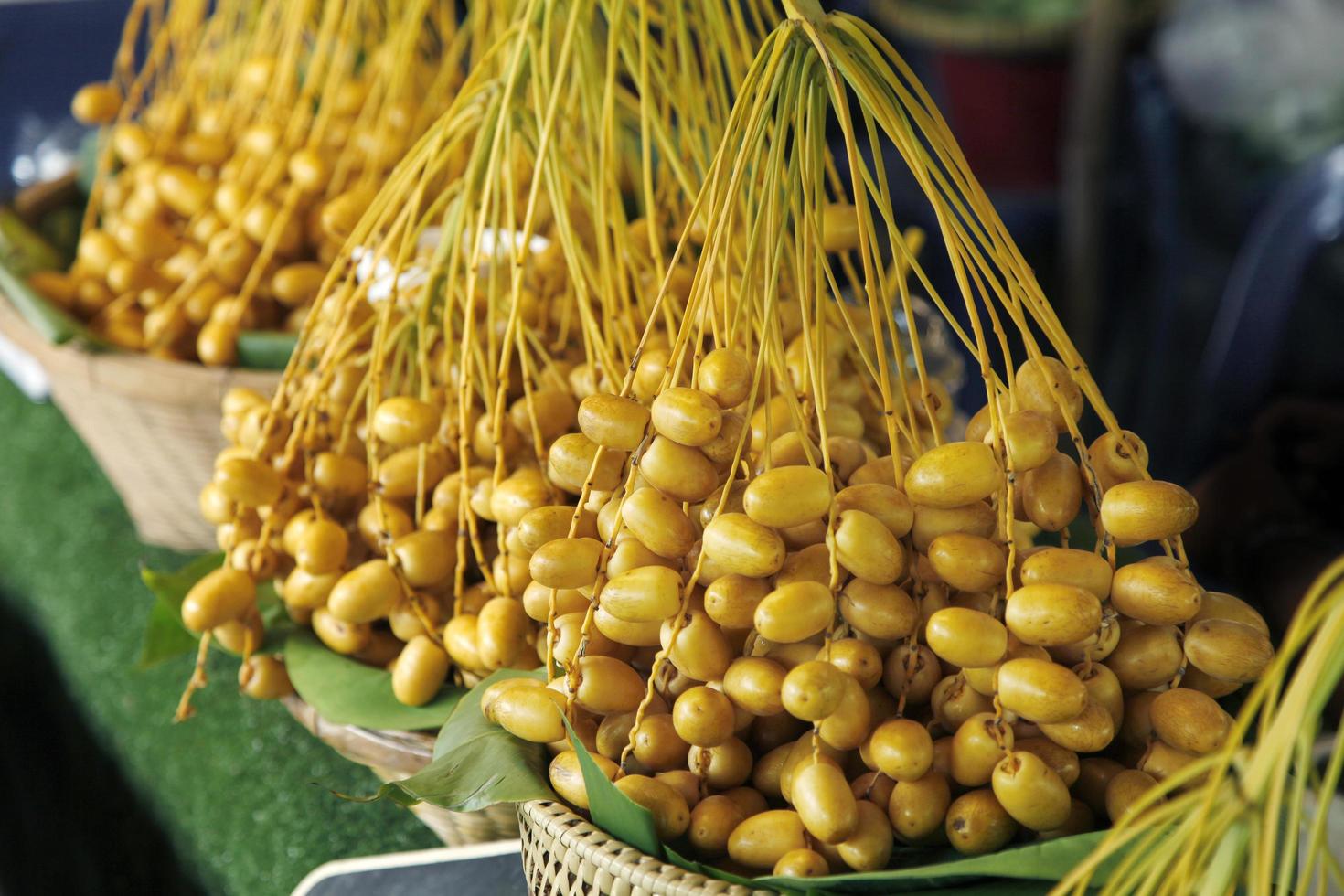 Dátiles amarillos crudos en el mercado tailandés, fruta sana foto