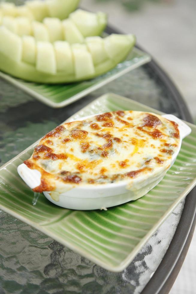 Espinacas al horno con queso en taza de cerámica en la mesa foto