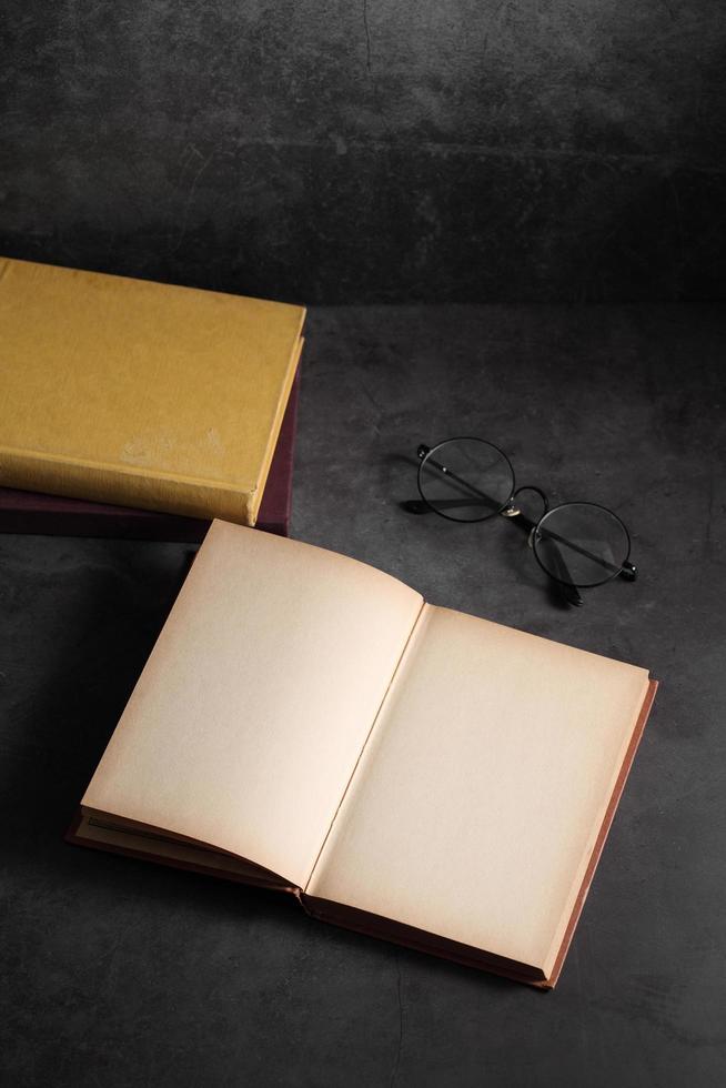 Old books and glasses open on table in library photo