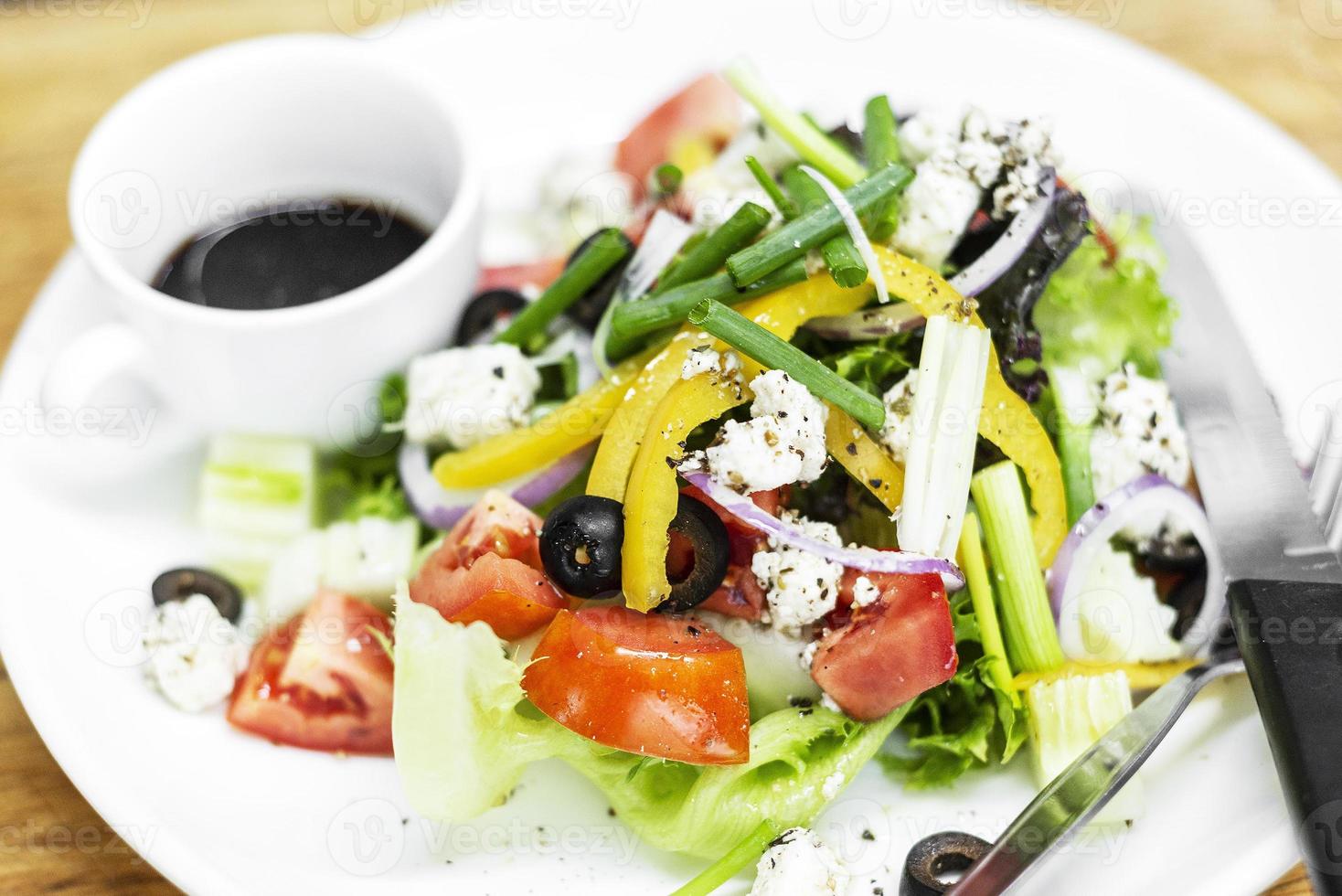 Traditional Greek salad with feta cheese and mixed organic vegetables on wooden table photo